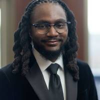 Man in suit smiling for a photo, blurred background